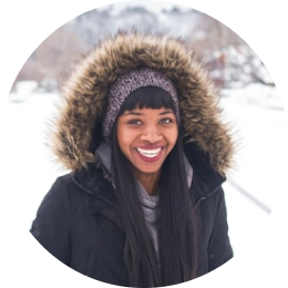 Smiling traveler bundled in a fur-lined hooded coat, enjoying Iceland's snowy landscape.