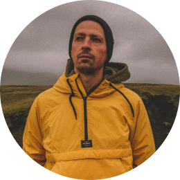 Traveler wearing a yellow rain jacket, standing in Iceland's moody, overcast landscape.