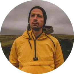 Traveler wearing a yellow rain jacket, standing in Iceland's moody, overcast landscape.