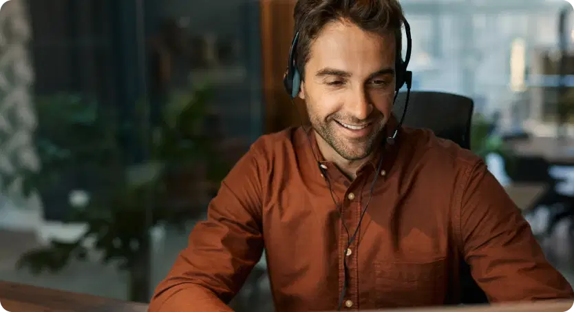 Smiling customer service representative wearing a headset, representing Cars Iceland's 24/7 support by local rental experts.