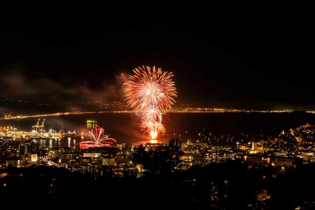 Colorful fireworks lighting up the night sky over a city in Iceland, celebrating a festive occasion and showcasing the vibrant atmosphere of local festivals.