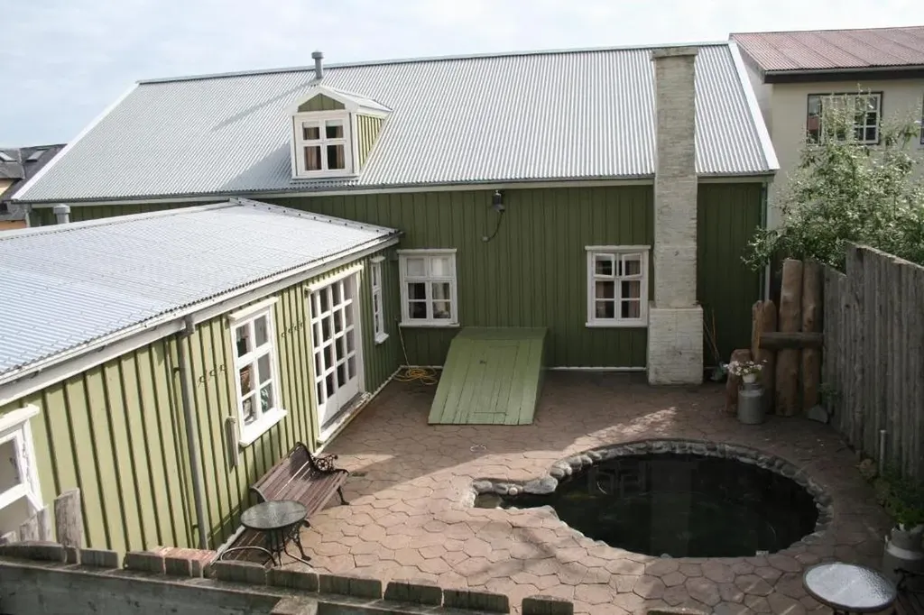 Cozy courtyard of Hótel Tindastóll in Iceland, featuring a traditional green and white building with a small hot tub, showcasing its quaint and inviting atmosphere.