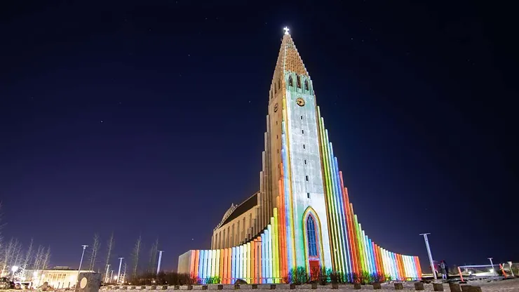 The Hallgrímskirkja church in Reykjavik illuminated with colorful lights at night, showcasing the vibrant atmosphere of events in Iceland.