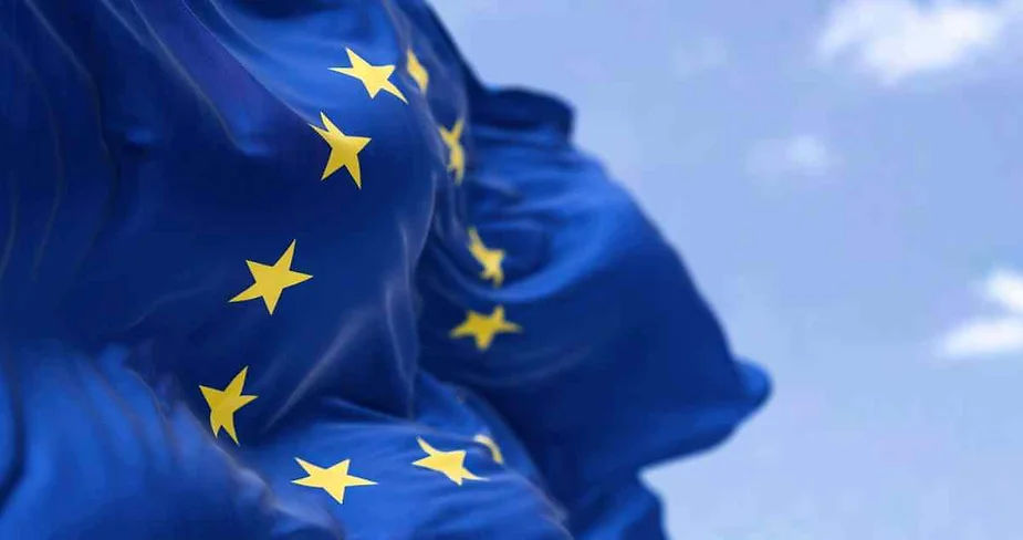 Close-up of the European Union flag waving with a blue sky in the background.