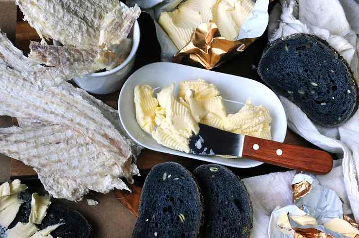 A close-up of traditional Icelandic food, featuring dark rye bread, butter, and dried fish, arranged on a table. The image highlights the unique culinary offerings during events in Iceland in March.