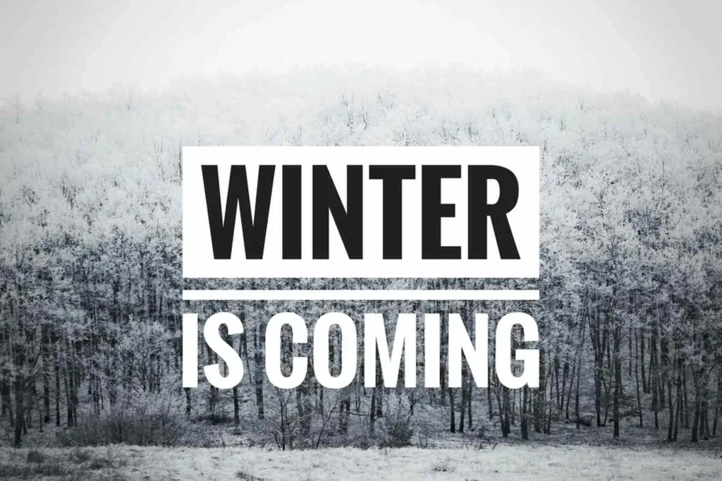 Winter landscape with frosty trees and 'Winter is Coming' text overlay in bold letters, Game of Thrones slogan