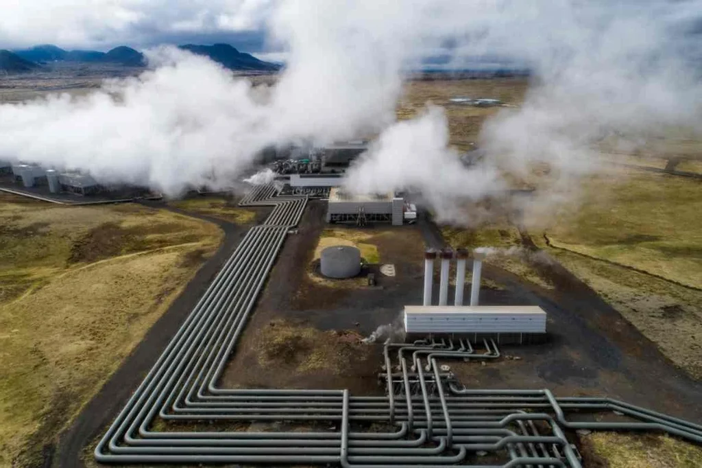 Aerial view of a geothermal power plant in Iceland with extensive pipelines and steam vents.