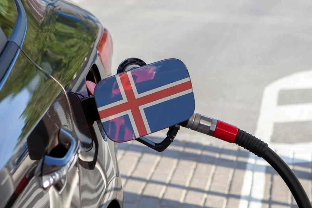 Close-up of a car being fueled at a gas station, with the fuel cap featuring the Icelandic flag.