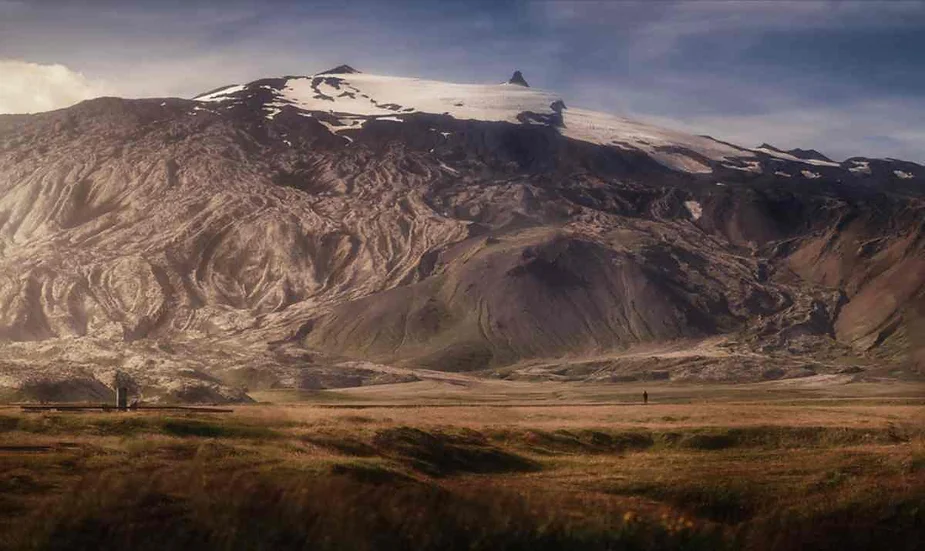 Majestic view of Iceland's snow-capped mountain, with a lush valley below, showcasing the island's dramatic and stunning landscapes.