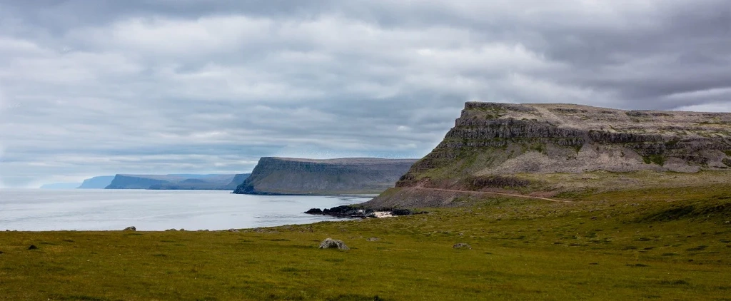 A breathtaking view of Hvitserkur, a unique rock formation, along the rugged coastline in Iceland, under a cloudy sky.