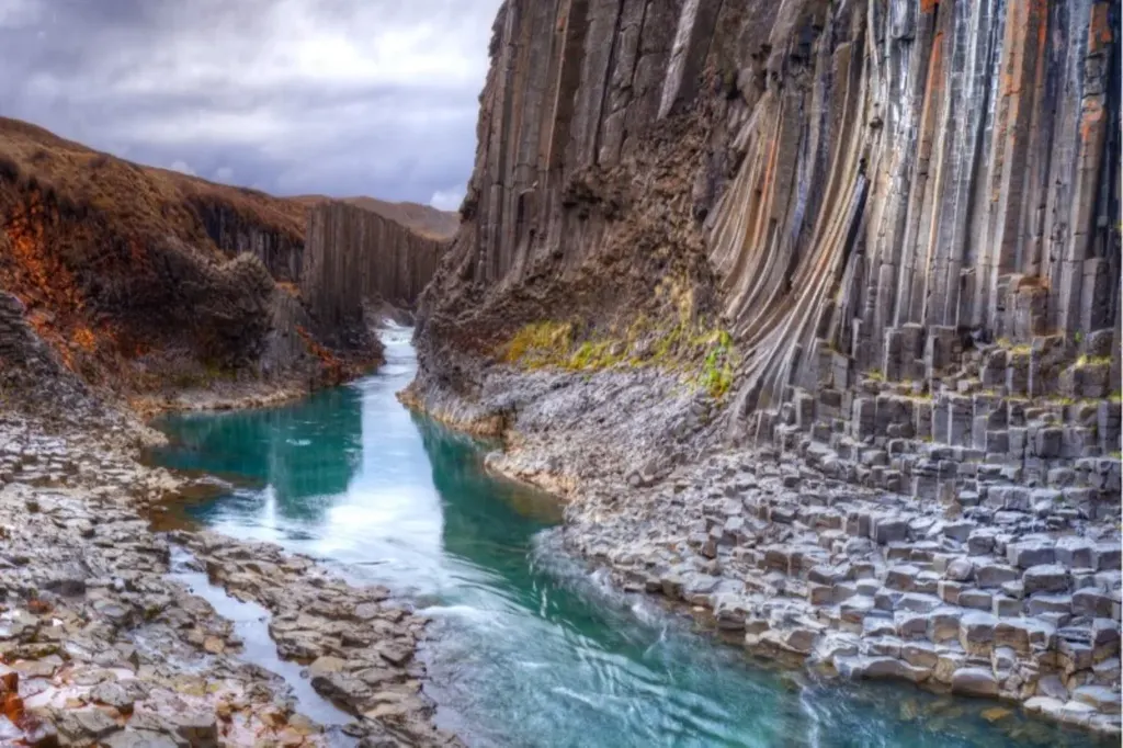 Breathtaking view of Stuðlagil Canyon with its unique basalt column formations and clear turquoise water in Iceland.