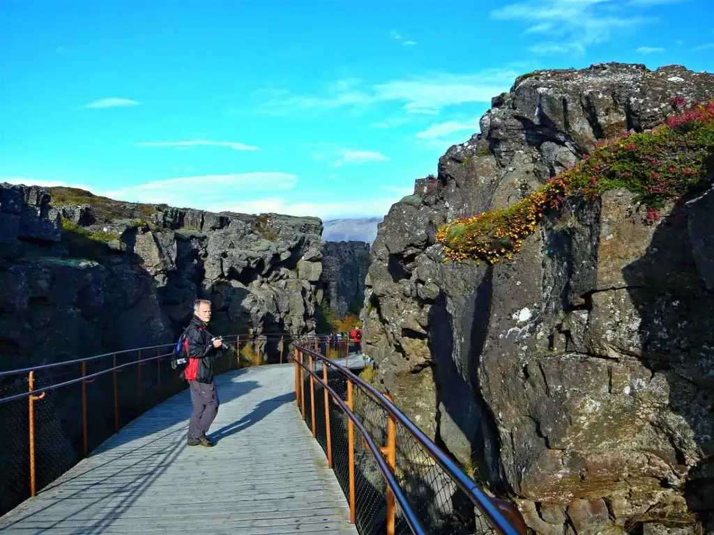 Snorkeler exploring the crystal-clear waters of the Silfra Fissure in Thingvellir National Park, Iceland, with dramatic underwater rock formations visible.