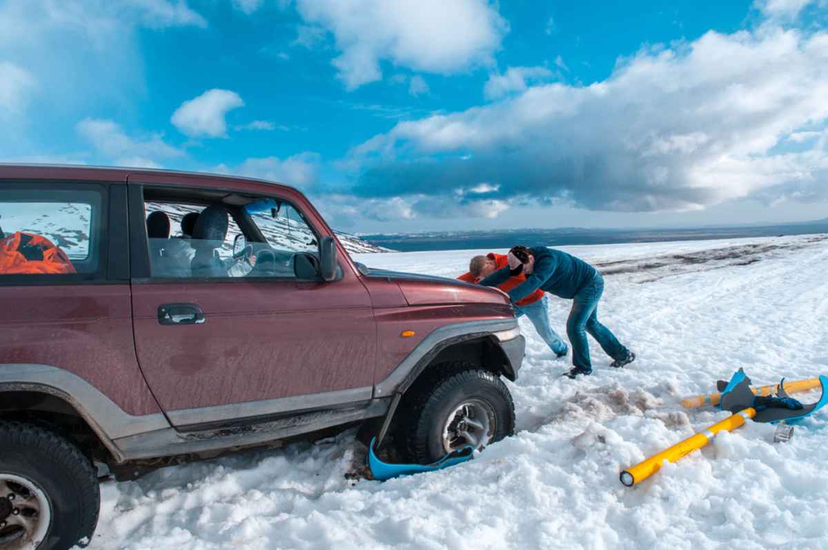 A group of people help tow a car after it was stranded in the snow