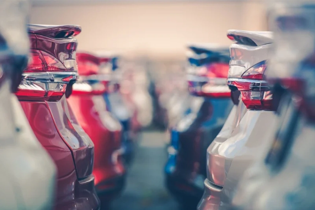 Close-up view of multiple parked cars in a dealership lot, showcasing the sleek design and modern taillights of various models.