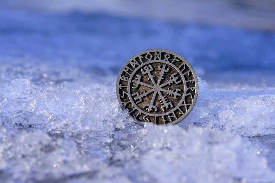 Norse Vegvisir amulet with runic inscriptions resting on glistening ice, symbolizing guidance and protection in the harshest conditions.