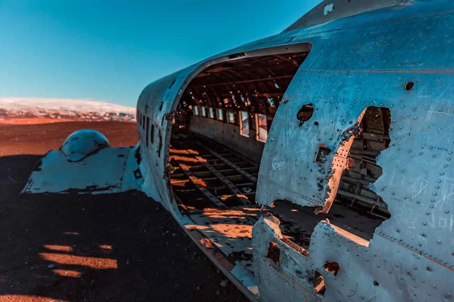 Close-up of the weathered and rusted remains of a plane wreck on Iceland's black sand beach, showing the interior structure.