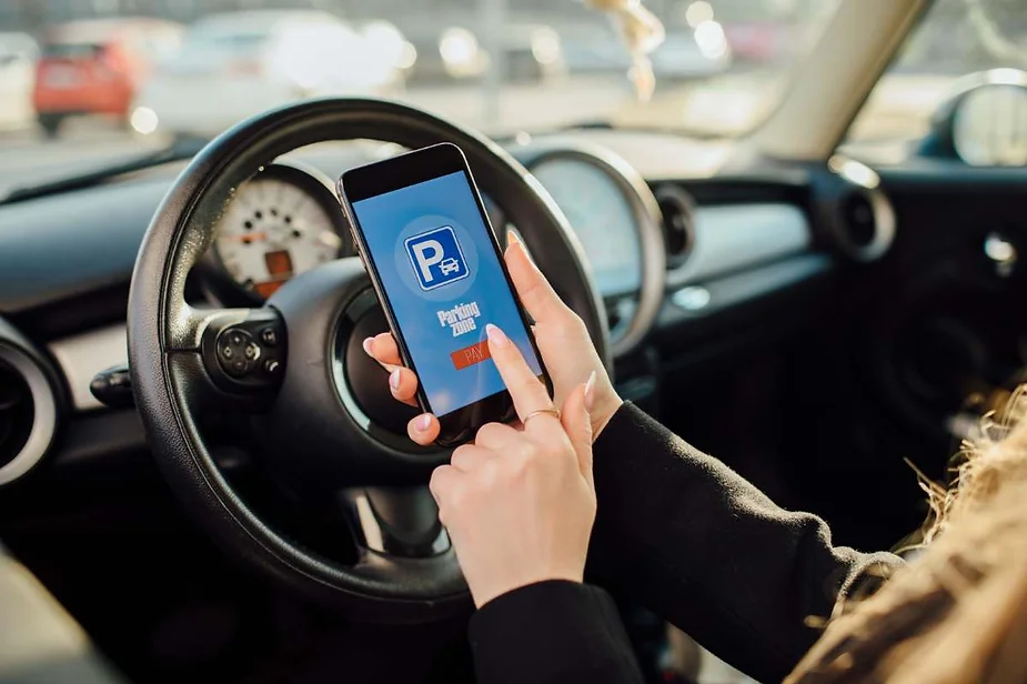 Person inside a car using a smartphone app to pay for parking.