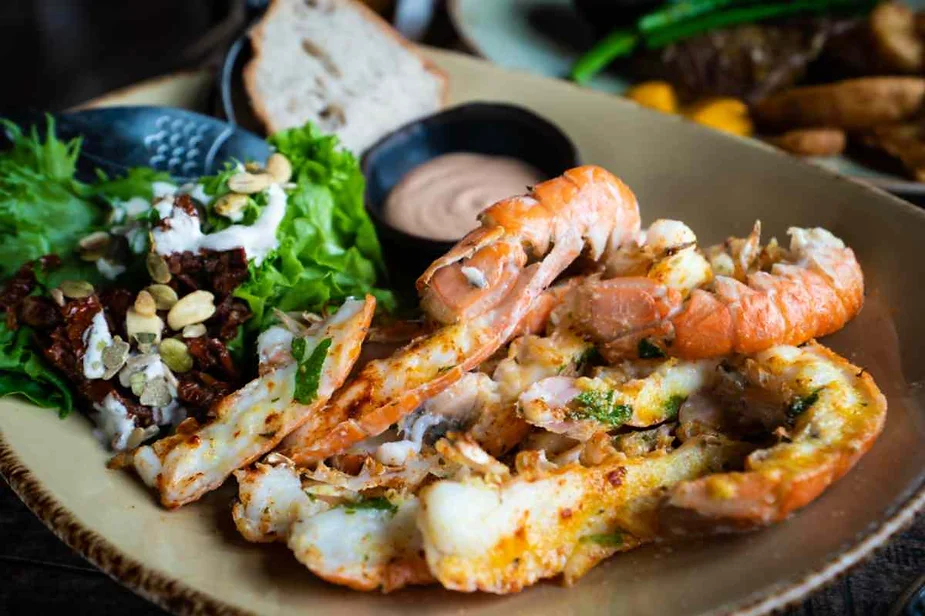 Delicious seafood dish with grilled shrimp, fresh salad, bread, and dipping sauce.