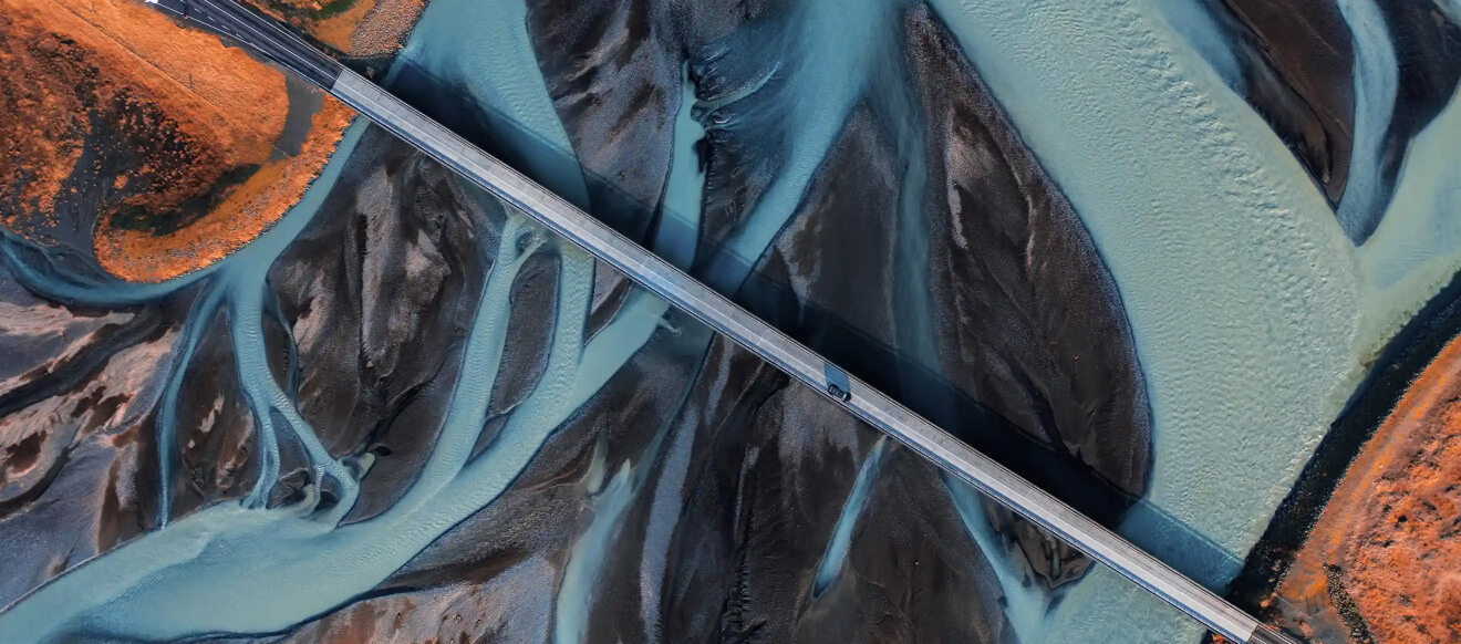 Aerial view of bridge crossing a beautiful constrasting landscape of black sand and turquoise river waters