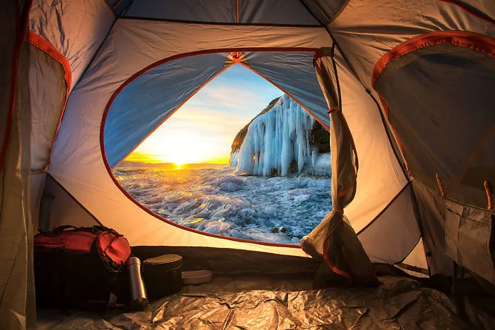 Camping tent with views to a frozen waterfall in winter