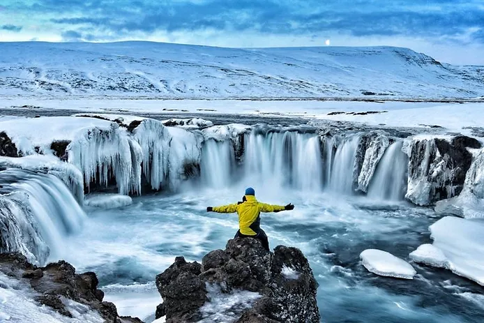 Tourist enjoying the views of a frozen waterfall 