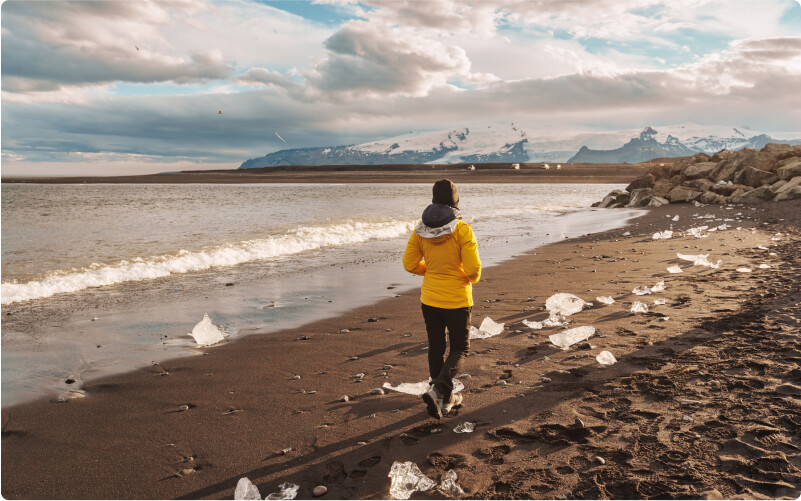 Traveler walking on Iceland's diamond beach in a yellow jacket