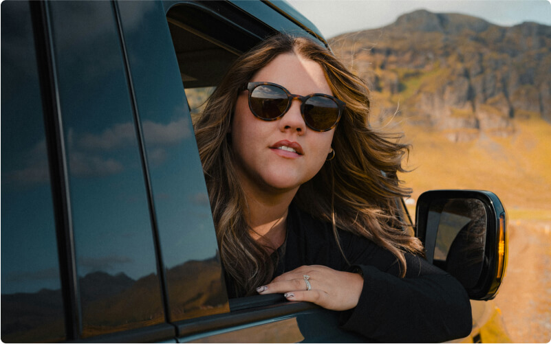 Driving a car on Iceland’s open roads, tourist with her sunglasses