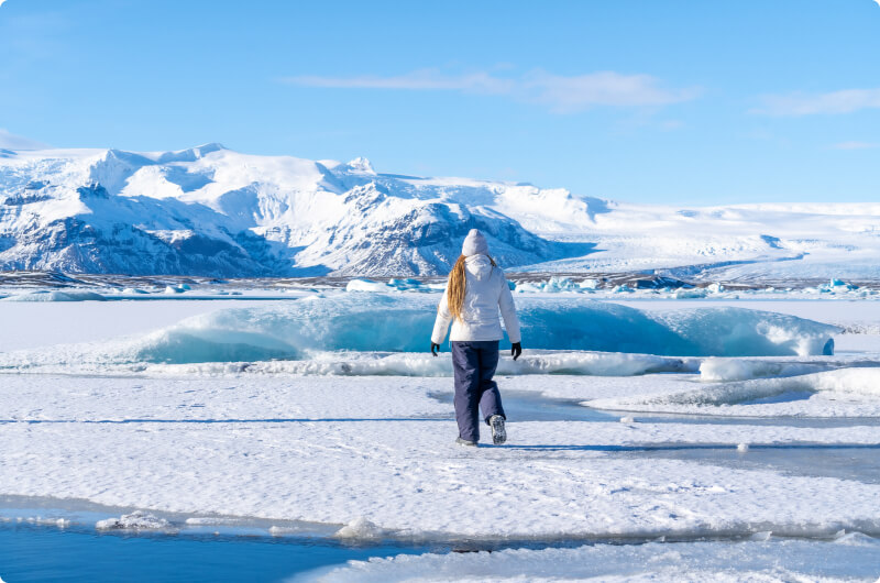 Traveler wearing an insulated jacket walking on top of a glacier