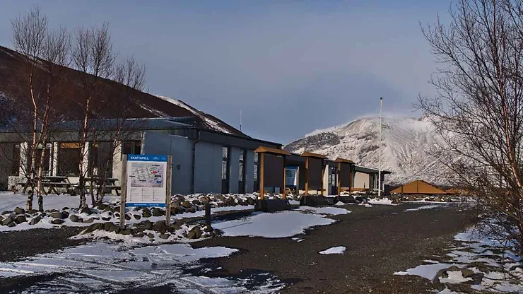 Snow-covered visitor center at Skaftafell National Park in Iceland, with barren trees and a mountain in the background.