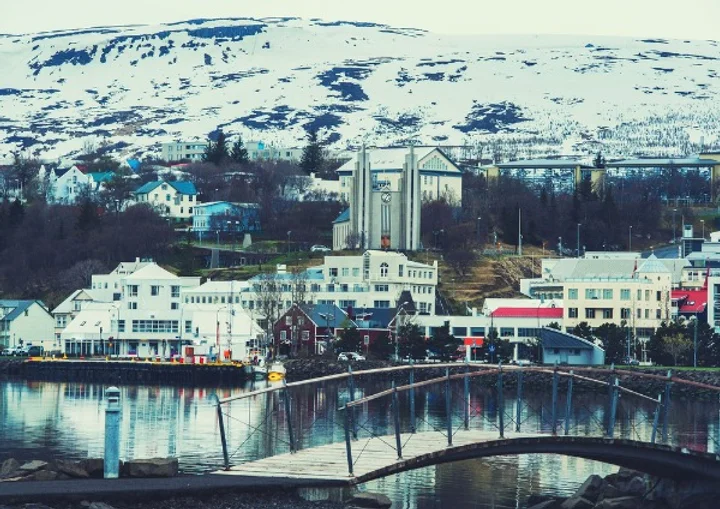 View of Akureyri, a charming town in northern Iceland, featuring traditional buildings with a snow-covered mountain backdrop.