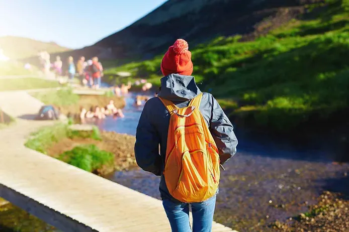 Girl with an orange backpack at Reykjadalur river 