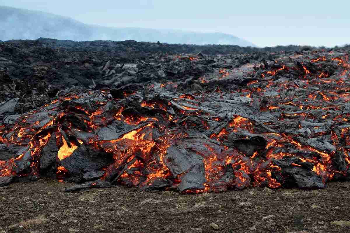 A close-up of a slowly moving lava flow, with glowing molten rock breaking through the dark, cooling crust as it advances across the landscape, capturing the raw power of volcanic activity.