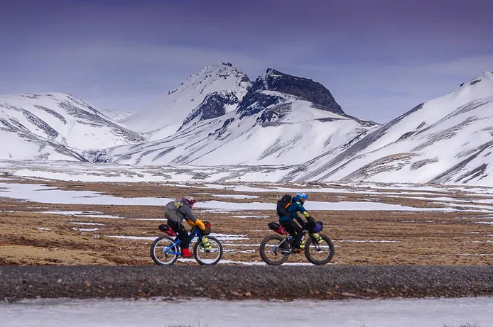 Two bikers against a mountain range backdrop