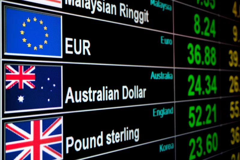 A digital display board showing various currency exchange rates, including the Euro, Australian Dollar, and British Pound Sterling, along with their respective flags, highlighting real-time financial data.