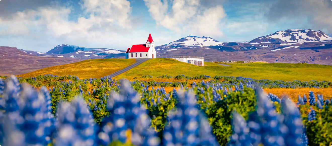 Cute redroof church on top of  ahill surrounded by a spring landscape with flowers