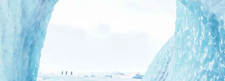 A serene and icy landscape captured from within an ice cave near Eyjafjallajökull in Iceland. The photograph frames the scene through the icy blue walls of the cave, providing a natural window into the snowy expanse outside. In the distance, three small figures walk across the snow-covered ground, emphasizing the vastness and isolation of the environment. The bright, overcast sky blends with the whiteness of the snow, creating a calm and ethereal atmosphere. The ice cave's walls display intricate patterns and textures, adding depth to the image and highlighting the cold beauty of the Icelandic wilderness.