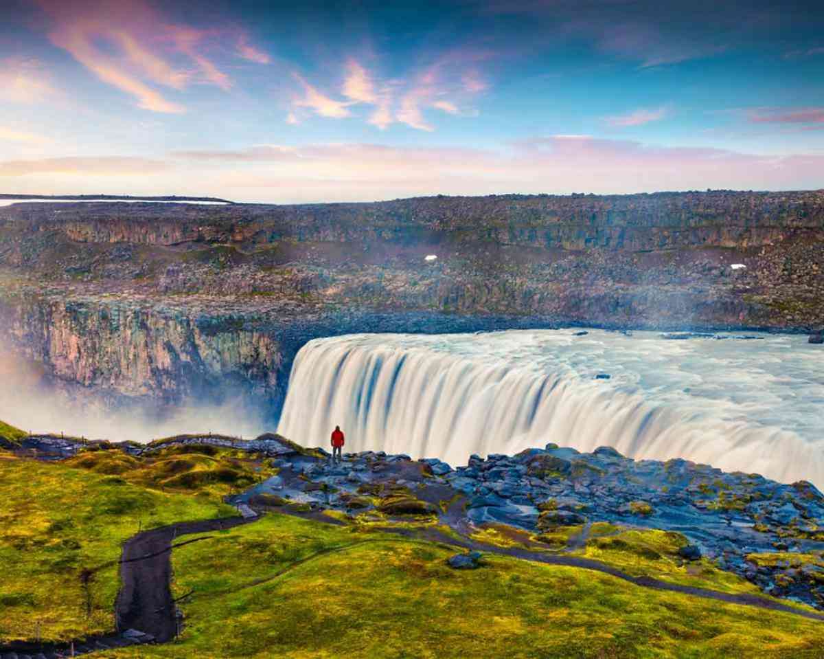 Dettifoss waterfall in Iceland during sunrise, surrounded by lush green cliffs, often included in guided tours with Selfoss waterfall.