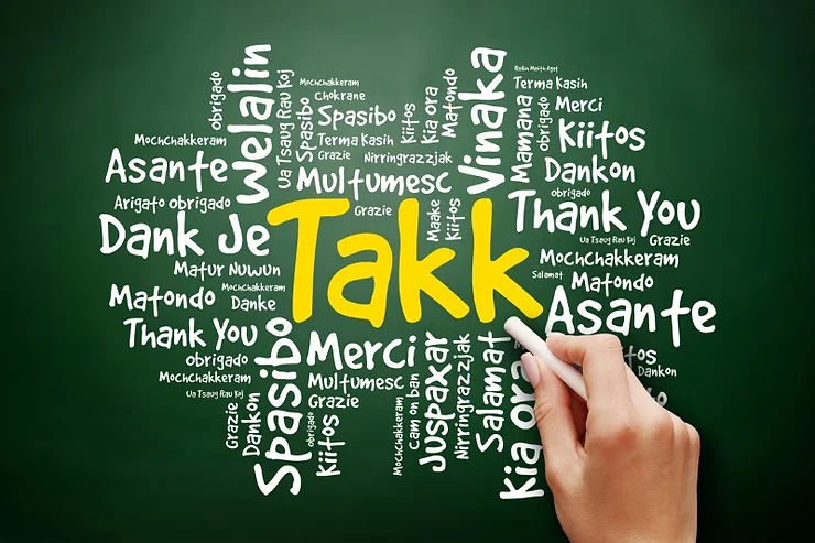 A blackboard with the word ‘Takk’ written prominently in the center, surrounded by ‘Thank You’ in various languages including Spanish, French, German, Japanese, and more.