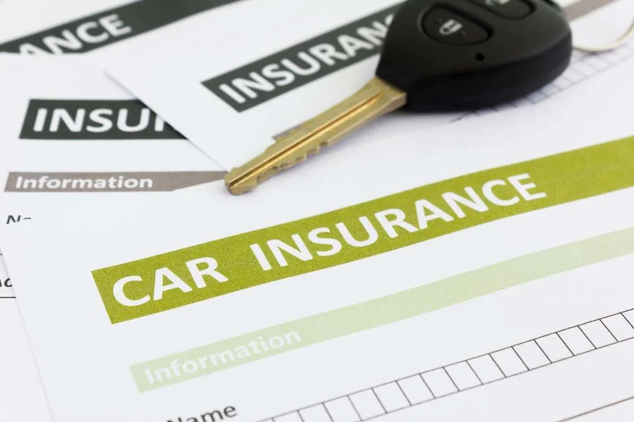 Close-up of car insurance documents and a car key, highlighting the importance of vehicle coverage and protection