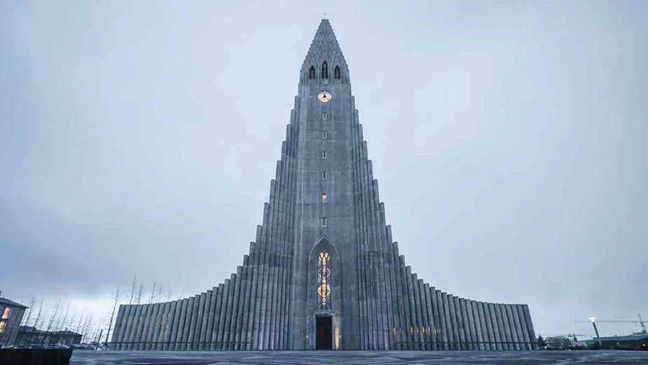 Front view of Hallgrímskirkja church in Reykjavik, Iceland, an iconic modernist structure with a towering concrete facade under a cloudy sky.