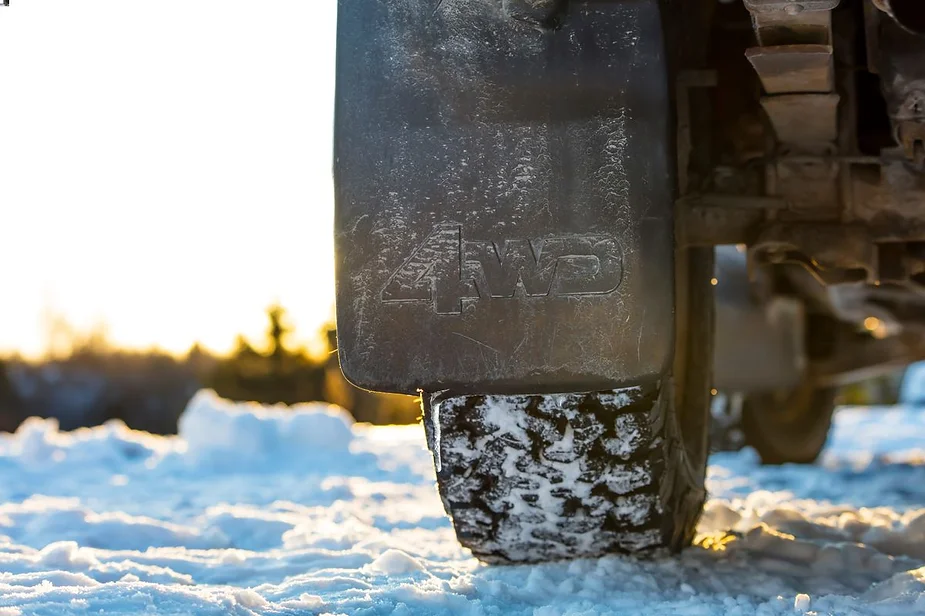 Close-up of a 4WD vehicle's tire and mudguard on a snowy terrain, highlighting off-road adventure capabilities in Iceland