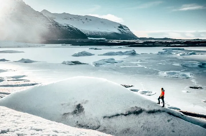 Tourist walking through snowy mountains in Iceland - Travel to Iceland - Cost guide for travelers