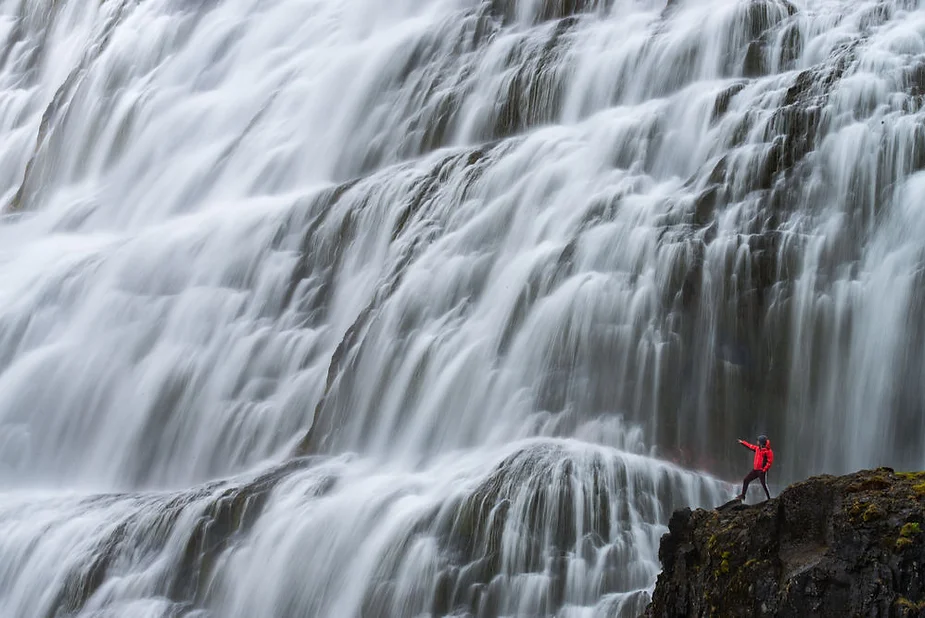 A breathtaking view of Dynjandi Waterfall in Iceland’s Westfjords, cascading down 100 meters in a bridal veil pattern, surrounded by rugged landscapes.