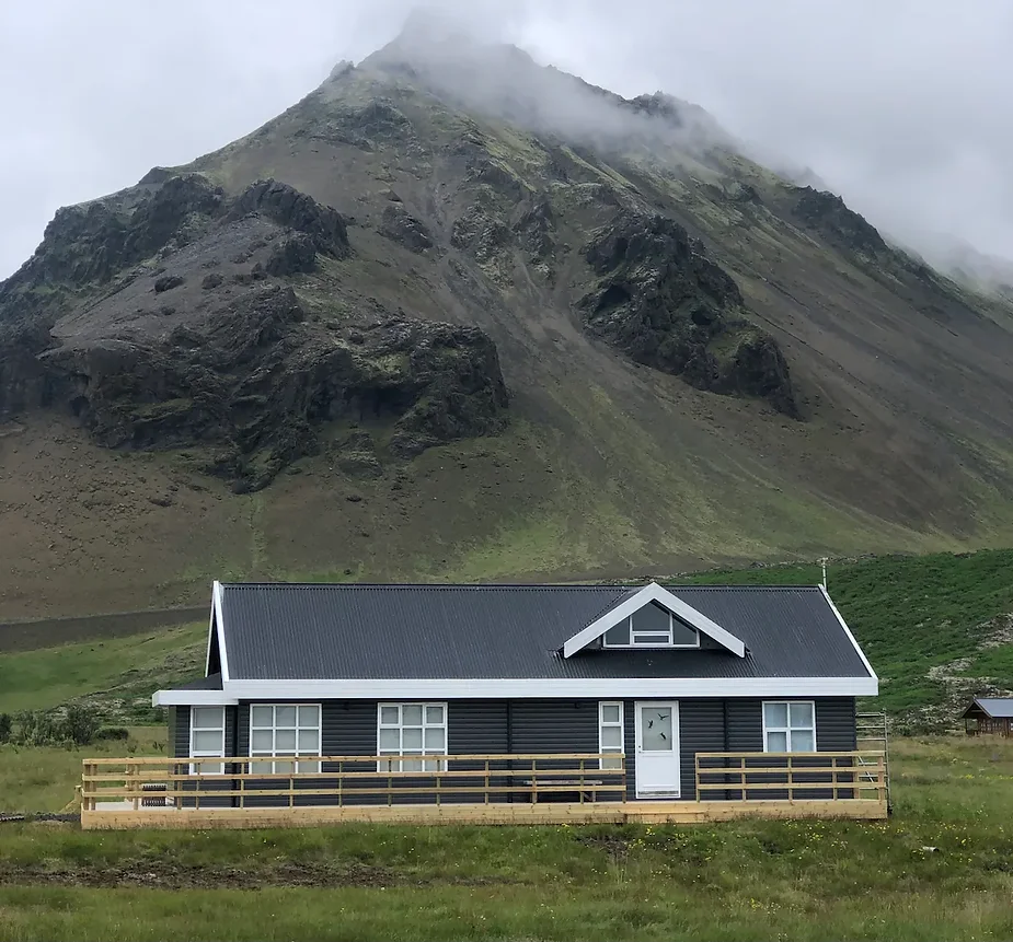 Newly renovated house in Arnarstapi, Iceland, surrounded by dramatic mountain views and featuring an outdoor hot tub and spacious family-friendly layout.