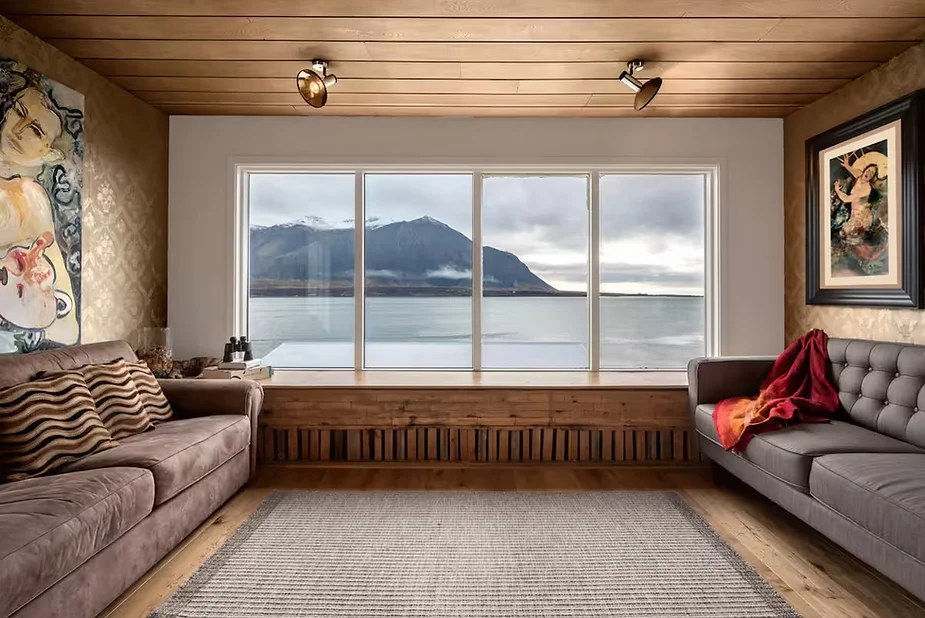 Art & Nature Retreat in Borgarnes, Iceland, featuring a cozy living room with panoramic bay views, Mid-Century Modern design, and beachfront access.