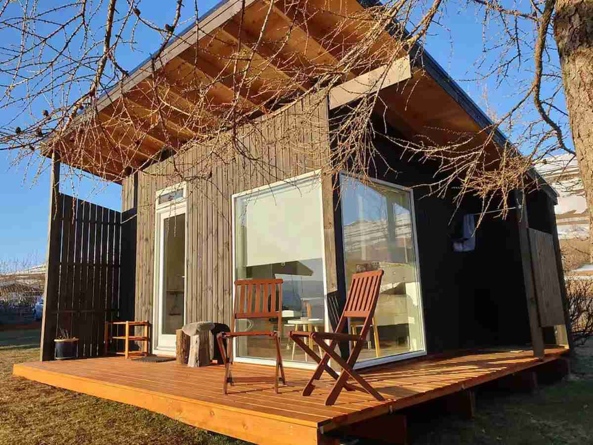 Charming eco-friendly rural cabin near Akureyri, Iceland, featuring a private deck, outdoor shower, and surrounded by lush trees with fjord views.