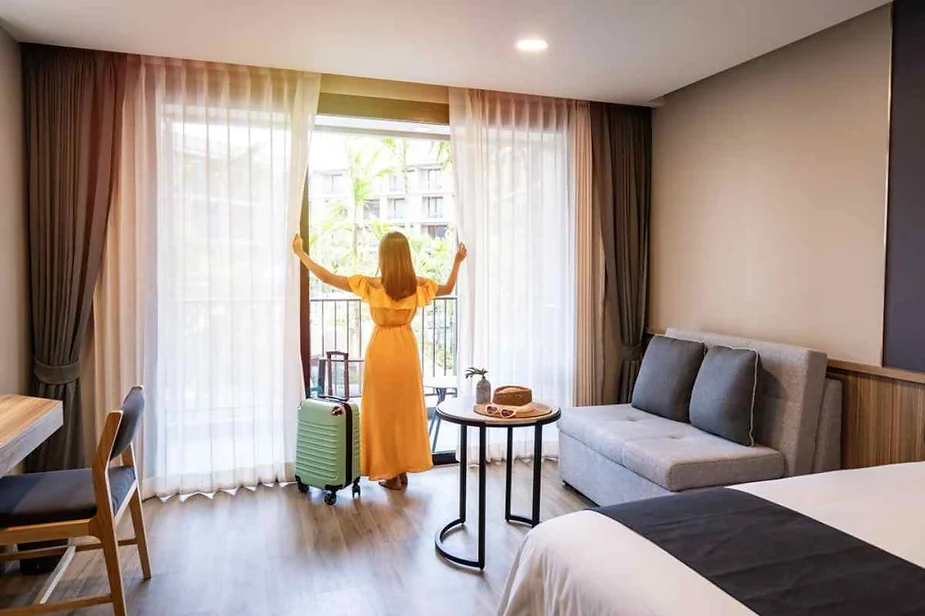 Person standing in a modern rental room, opening curtains to reveal scenic views, representing the ideal amenities for Iceland vacation rentals.