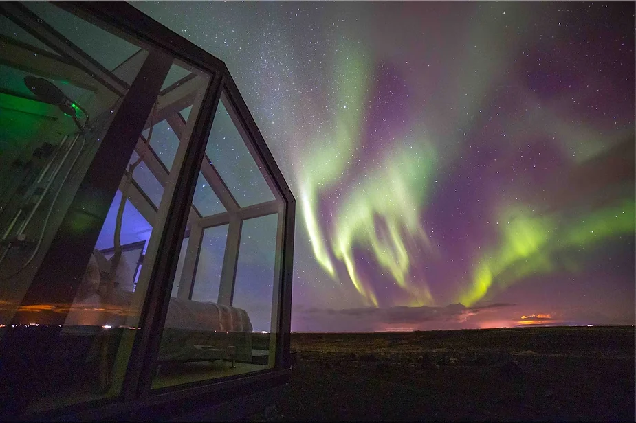 Glass-walled cottage in Hella, Iceland, designed for Northern Lights viewing with a private hot tub and stunning volcanic landscapes.