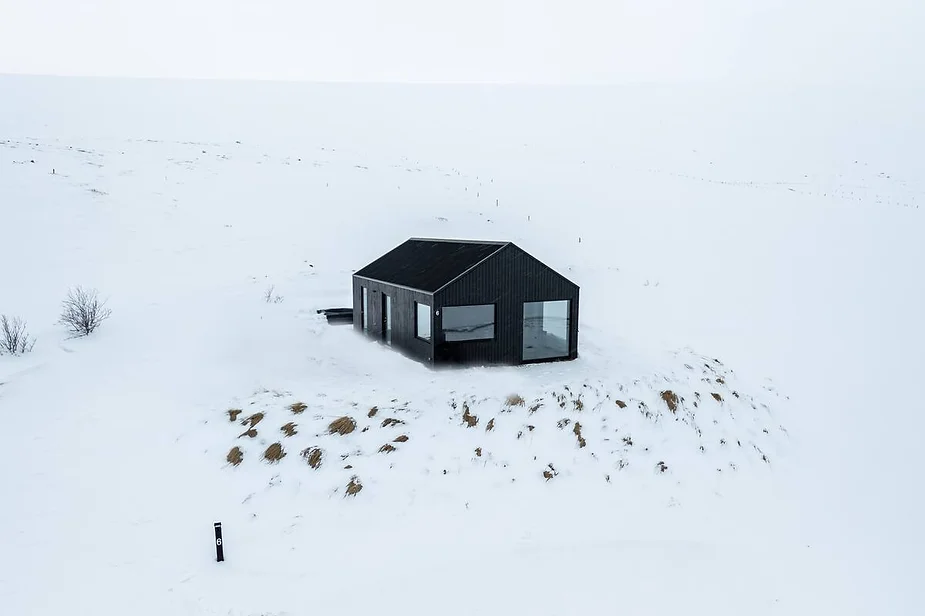 Svartaborg Luxury Villa in North Iceland, a modern black villa set in a snowy valley with panoramic mountain views near Húsavík.