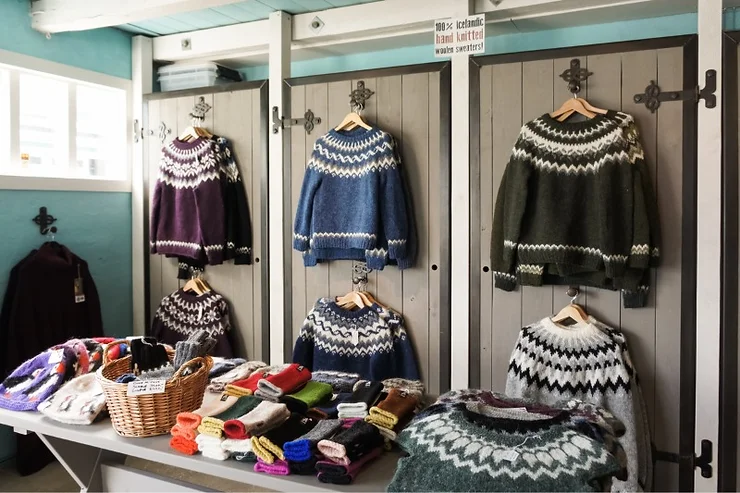 A variety of Icelandic sweaters on display in a shop, showcasing traditional knitwear patterns.